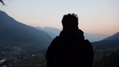 Silhouetted-Person-At-Mountain-Top-Overlooking-The-Himalayan-Town-Of-Manali-In-India