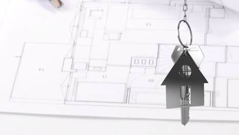 house keys and key fob hanging over architectural drawing in the background