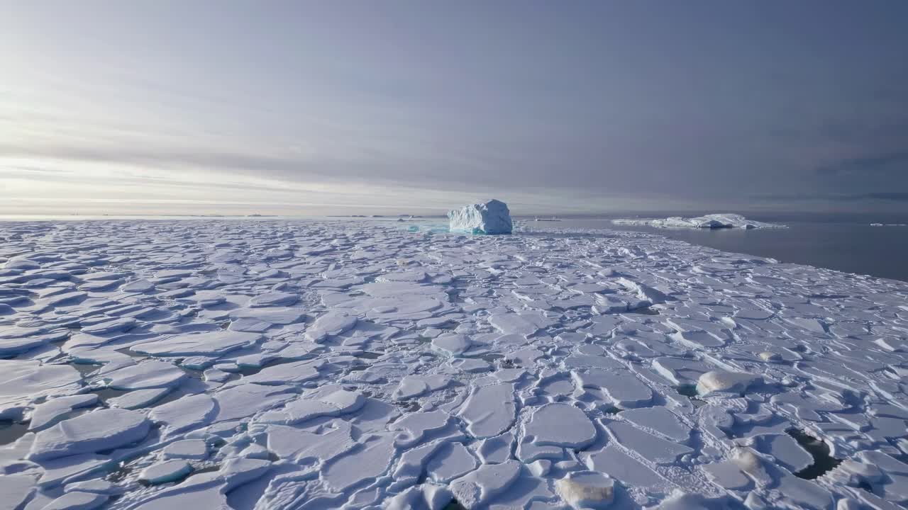 Aerial video captures vast icy landscape with scattered ice floes under a cloudy sky