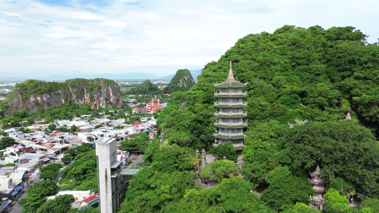 Aerial establishing of Marble Mountains in Da Nang, Vietnam with lush greenery and pagoda, ascend overview