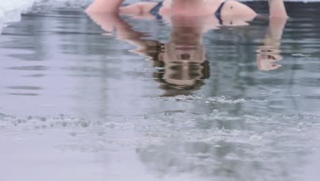 A young woman is swimming in winter