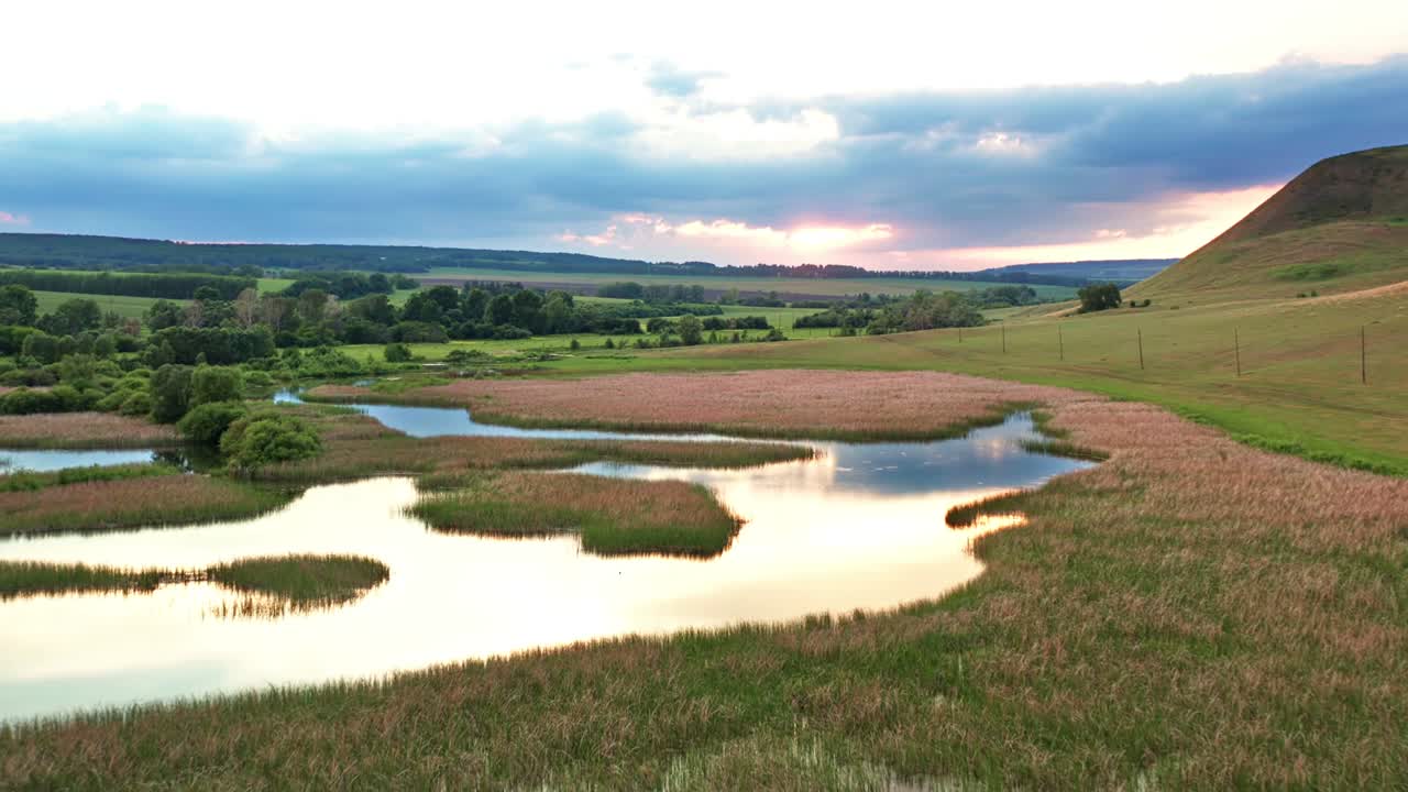 la frescura de la mañana y la belleza de los prados cubiertos de flores rosadas. la calma agua limpia en los lagos refleja el cielo. altas montañas y colinas en la niebla en el fondo.