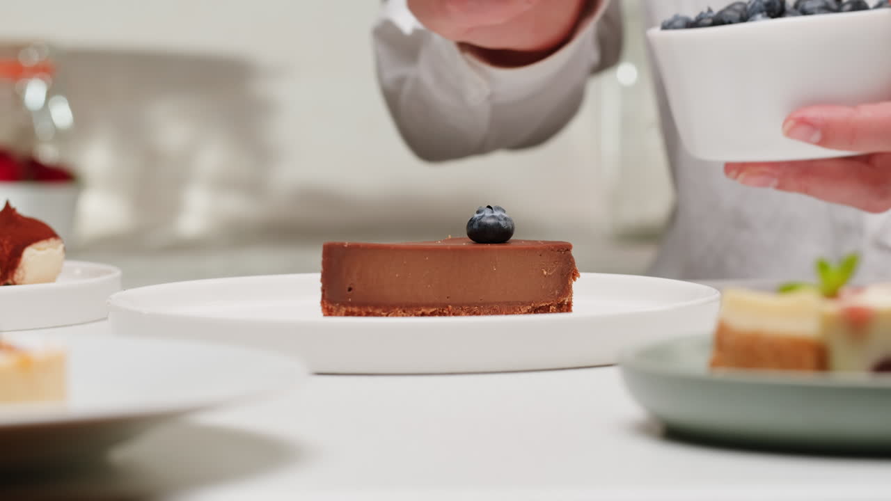 Chef placing a blueberry on top of a chocolate cheesecake