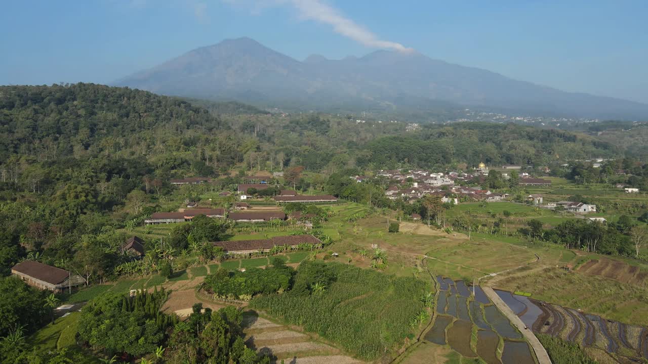 Countryside aerial footage of Indonesian rural community with mosque, paddy terraces, and green agricultural land