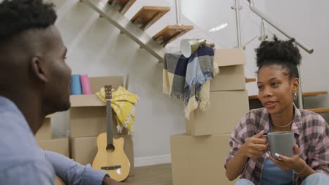 Video-of-happy-african-american-couple-drinking-coffee-after-moving-into-new-house