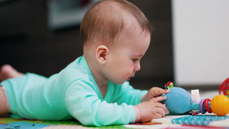 adorable baby yawning sweetly lying on his belly. lovely kid is interested with a toy. beautiful toddler showing tongue to the camera.