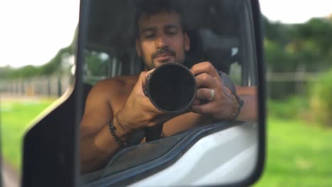 This image is a self-portrait taken from inside a vehicle, with the photographer visible in the side mirror. The person is holding a camera, capturing his own reflection
