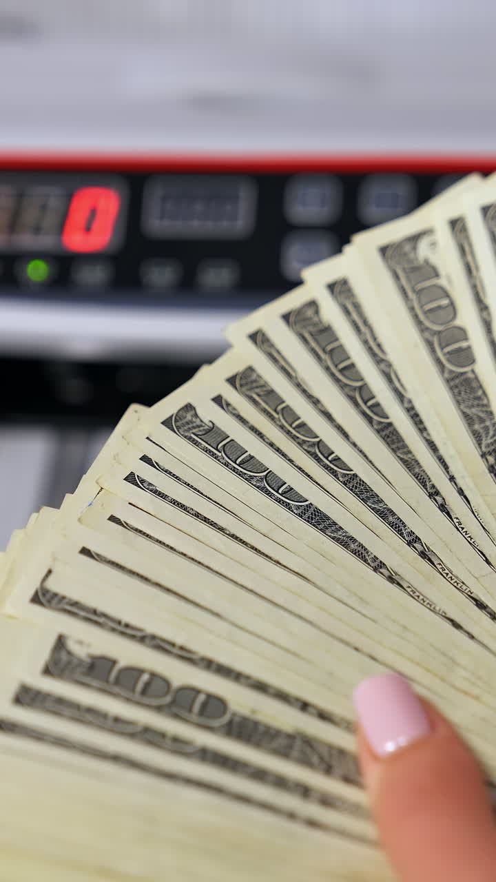 Hand holding a fan of 100 dollar bills