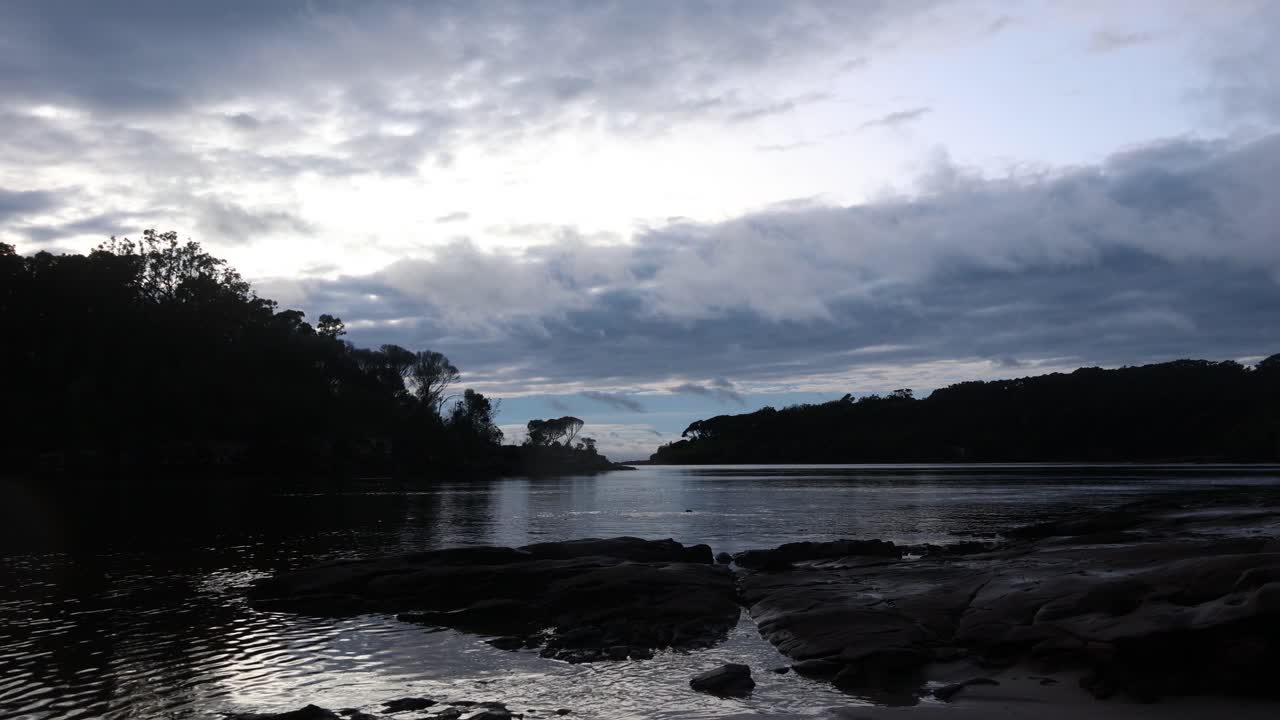 lapso de tiempo de nubes moviéndose sobre una tranquila bahía oceánica en la costa sur de nsw