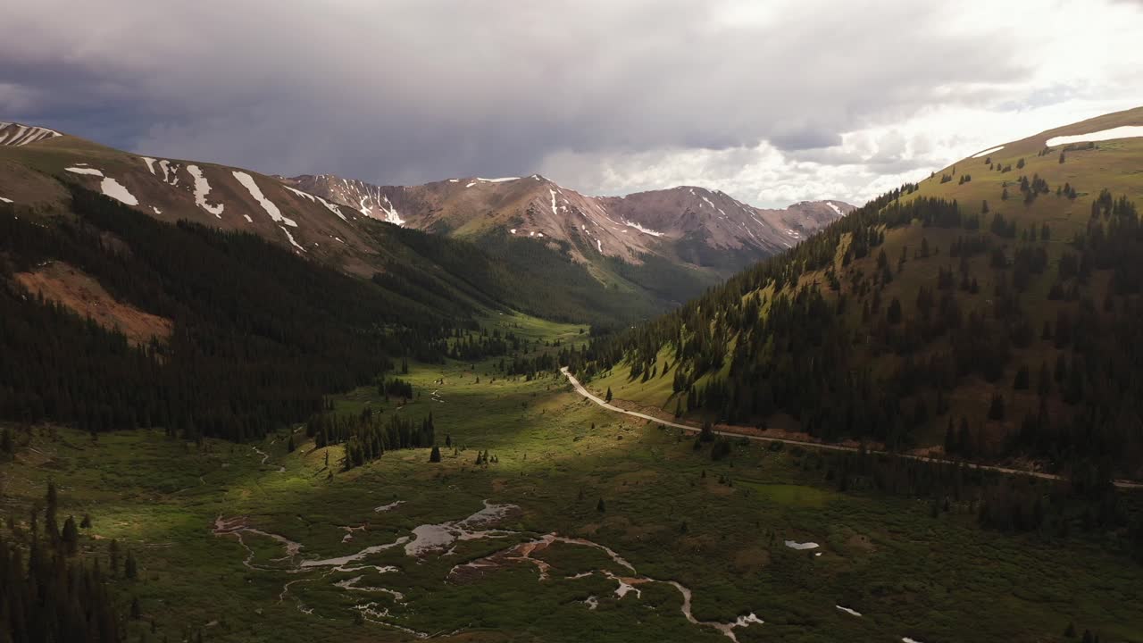 Aerial View of a scenic, moody, and green mountain valley range with winding road in the Rocky Mountain area of Colorado