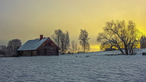 Tiro-De-Lapso-De-Tiempo-De-La-Mística-Puesta-De-Sol-Dorada-Detrás-De-Densas-Nubes-Durante-El-Día-De-Invierno-Cubierto-De-Nieve-En-La-Zona-Rural-Con-Casa-De-Campo