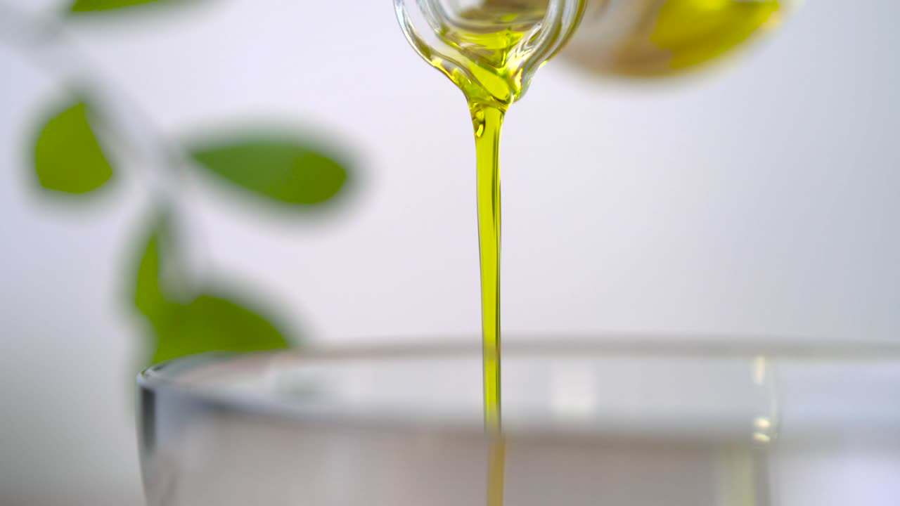 verter aceite de oliva virgen en un cuenco de vidrio para ensalada en la cocina