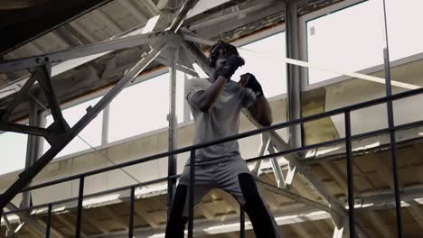 Joven-Boxeador-Masculino-Practicando-Boxeo-De-Sombra-Alrededor-De-Las-Estructuras-Metálicas-En-El-Interior