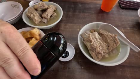 adding sauce to a traditional singaporean dish