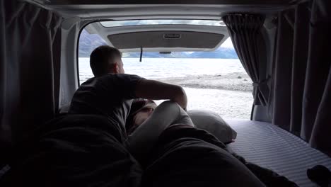 couple enjoying scenic lake and mountain view from camper van