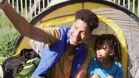 Feliz-Hombre-Birracial-Y-Su-Hijo-Tomando-Selfies-Usando-Un-Teléfono-Inteligente-En-El-Jardín