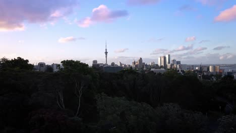 Sky-tower-and-colorful-Skyline-of-port-city-of-Auckland-at-dusk,-Revealing-aerial