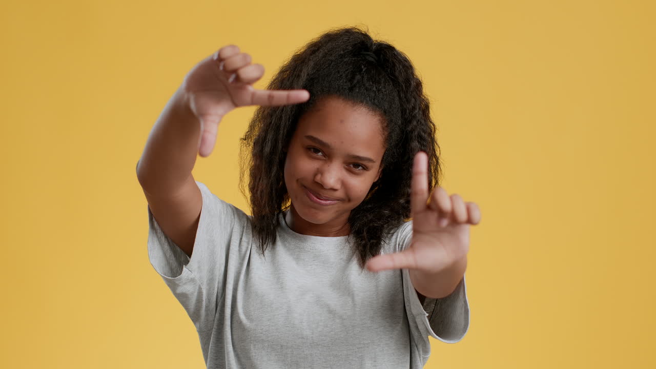 una adolescente posando con las manos enmarcando una sonrisa