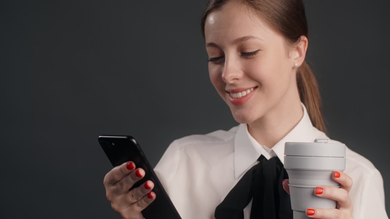 Businesswoman using a smartphone and drinking coffee