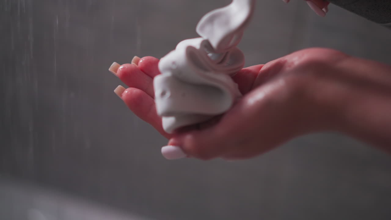 Woman pumps shaving foam on palm in bathroom closeup. Lady applies skin care mousse for hair removal in shower cabin. Healthy cosmetic product