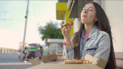 woman eating pizza outdoors