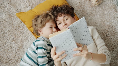 mother and son reading a book on the floor
