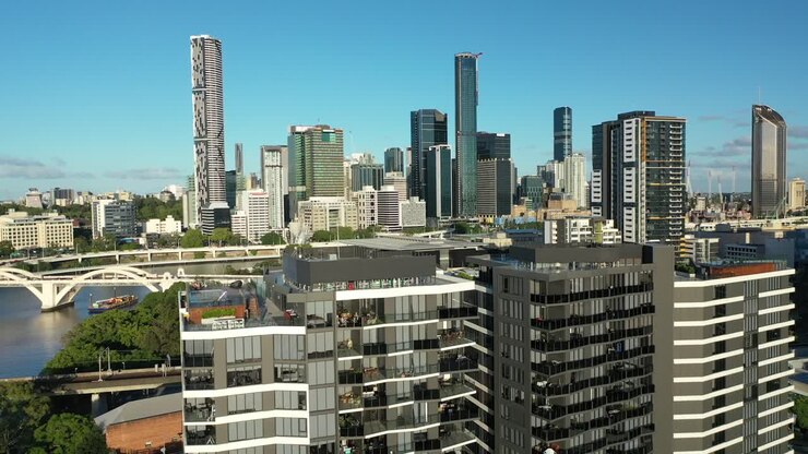 Vivencie a beleza deslumbrante de Brisbane com esta imagem de drone de dois edifícios de apartamentos em West End, tendo como pano de fundo o icônico horizonte da cidade e o rio, tirada ao meio-dia com céus azuis límpidos