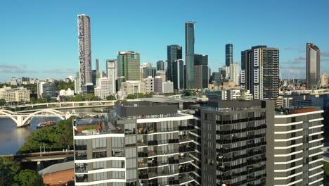 experience the stunning beauty of brisbane with this drone shot of two apartment buildings in west end, set against the iconic city skyline and river, taken at mid-day with clear blue skies