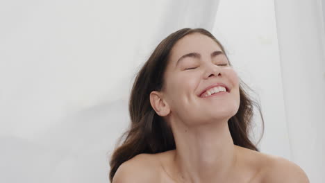 slow motion portrait beautiful young woman rose petals falling on attractive female smiling enjoying luxury between sheets in white background beauty concept