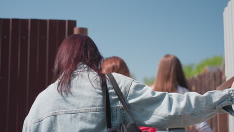 close up of three women enjoying lively conversation outdoors on sunny day, wearing sunglasses and casual outfits, captured while smiling and walking together with ease in natural light setting