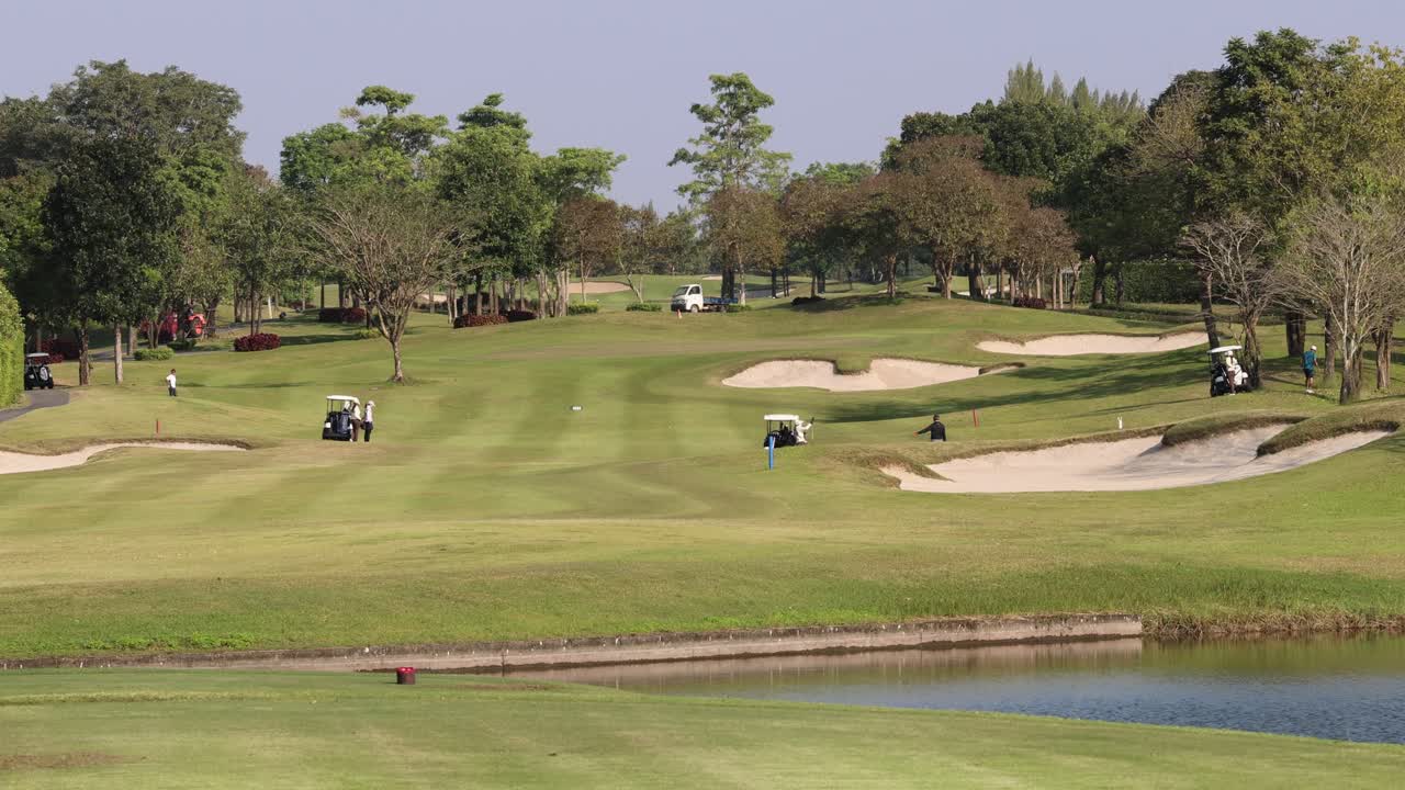 골퍼 들 과 카트 들 이 울창 한 코스 를 가로질러 이동 하고 있다
