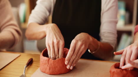 women shaping clay bowls in a pottery class