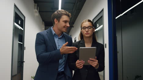 Office-mentor-checking-trainee-report.-Focused-business-team-walking-hallway