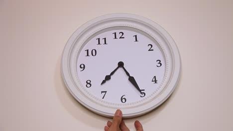 hand adjusting or repositioning a clock on the wall, close up