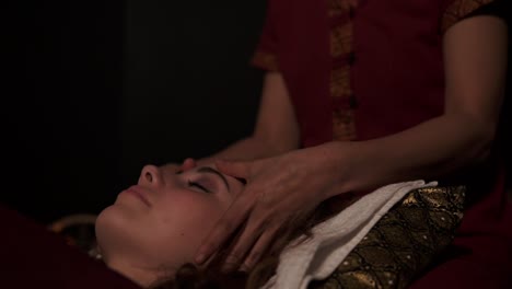 Massage-therapist-does-thai-massage-of-neck,-head-and-face-for-woman-on-couch-in-spa-room.-Slow-motion-shot