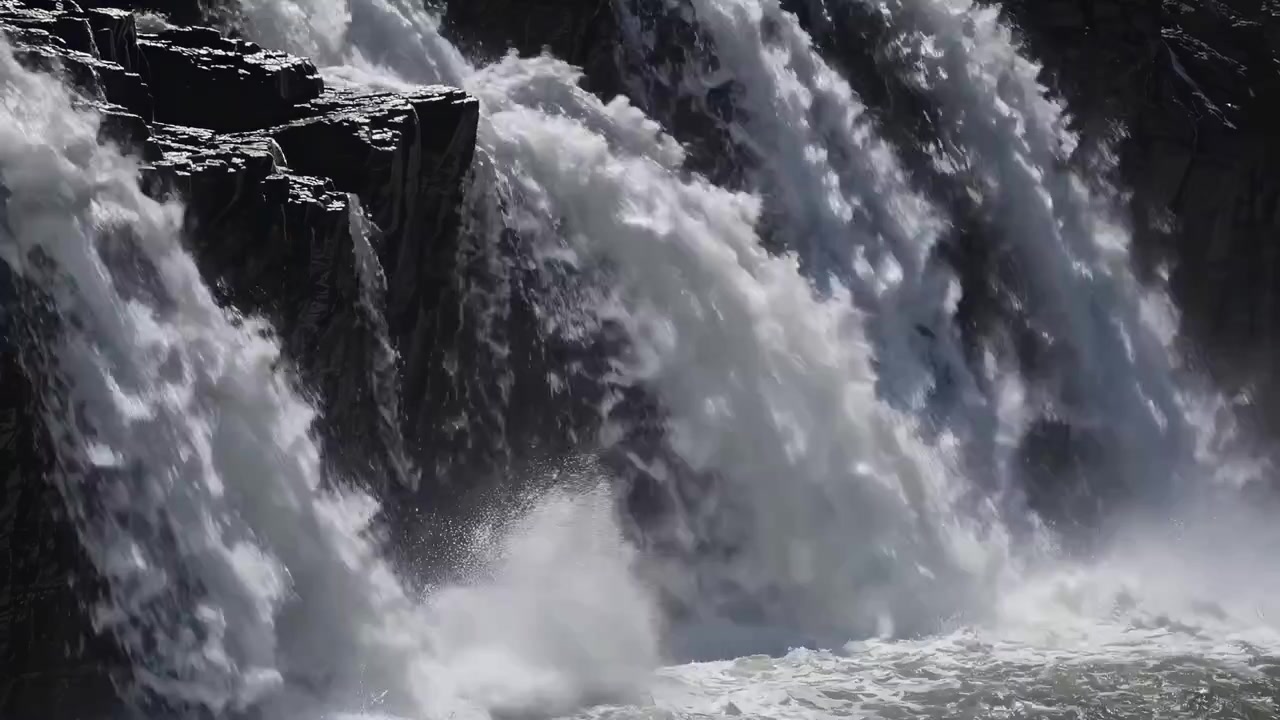 Powerful Waterfall Cascading Over Dark Rocky Cliffs