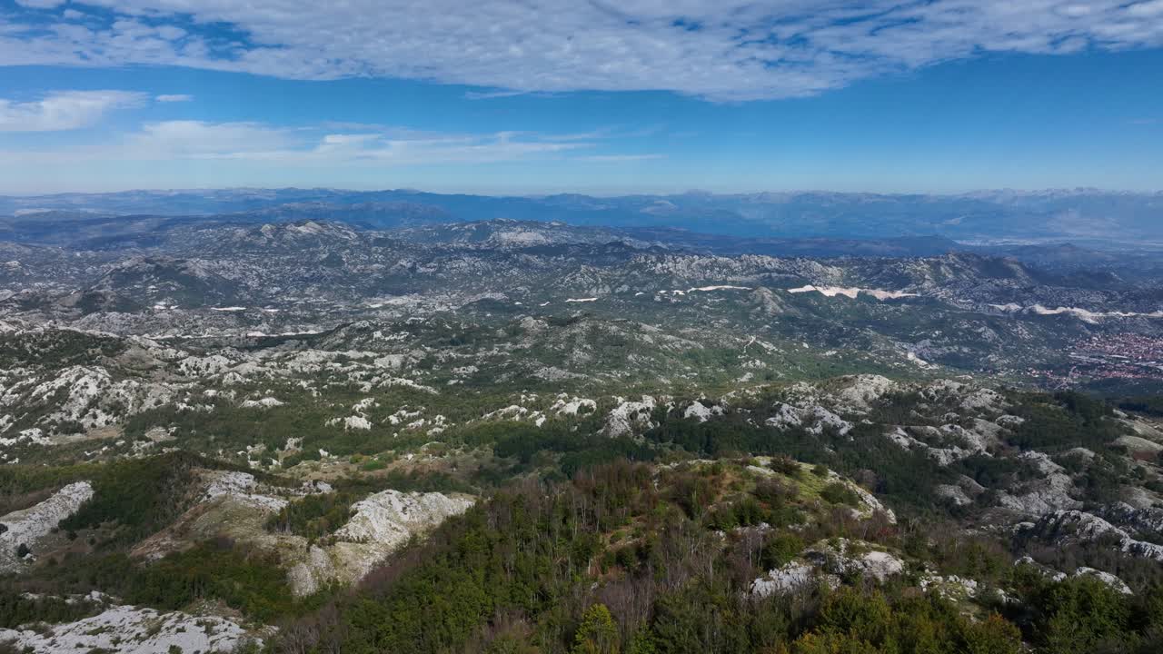 A scenic view of rolling hills and green mountains in Lovćen, Montenegro, stretching to the horizon.
