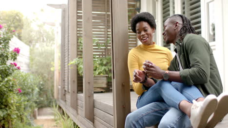 laughing together, african american couple sitting on porch, enjoying quality time at home