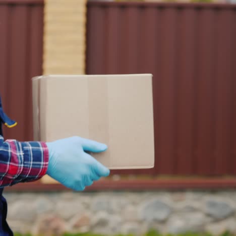 side view: a courier with a parcel of hands walks along the street