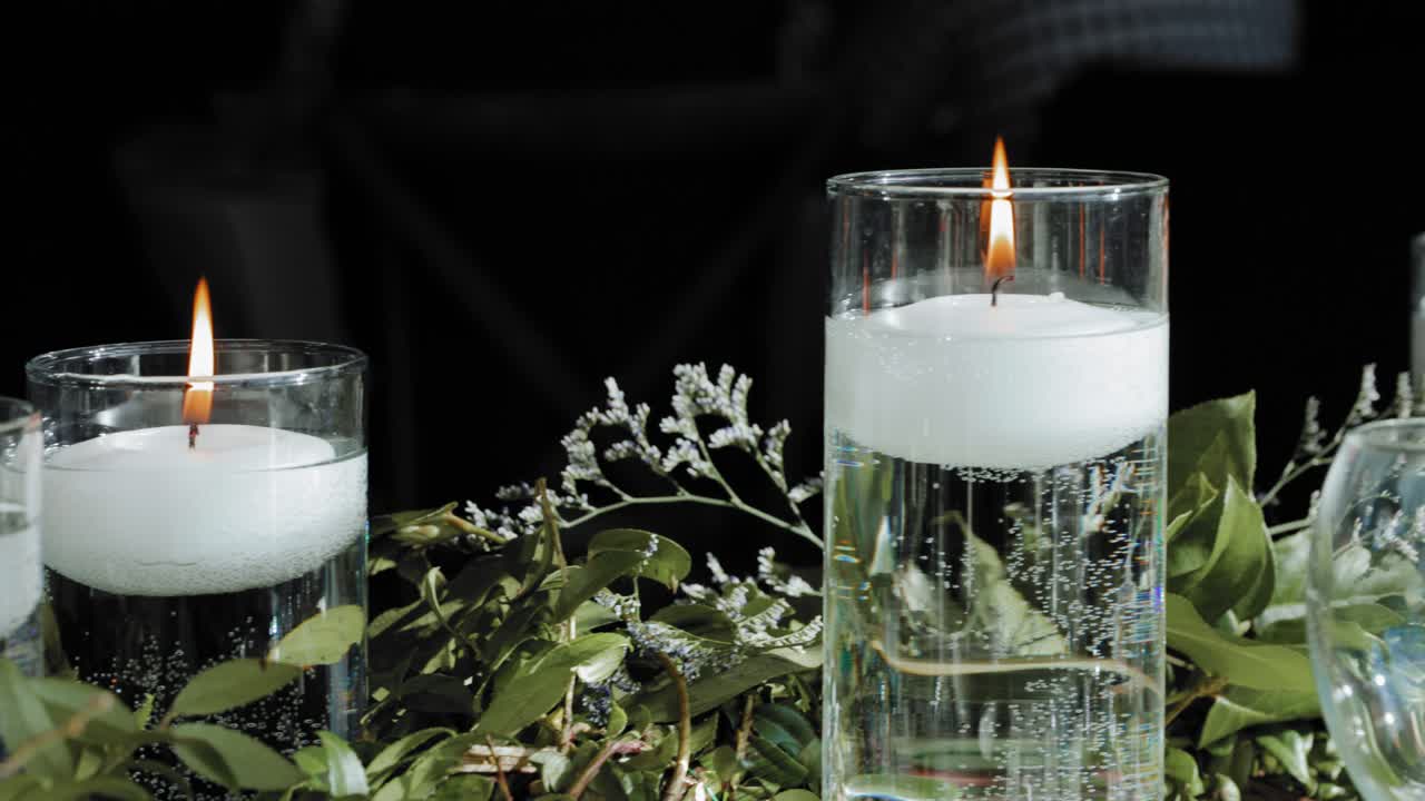 Splendida composizione piatta di decorazioni per tavolo nuziale con candele bianche accese galleggianti in vasi e bellissime composizioni floreali di piante