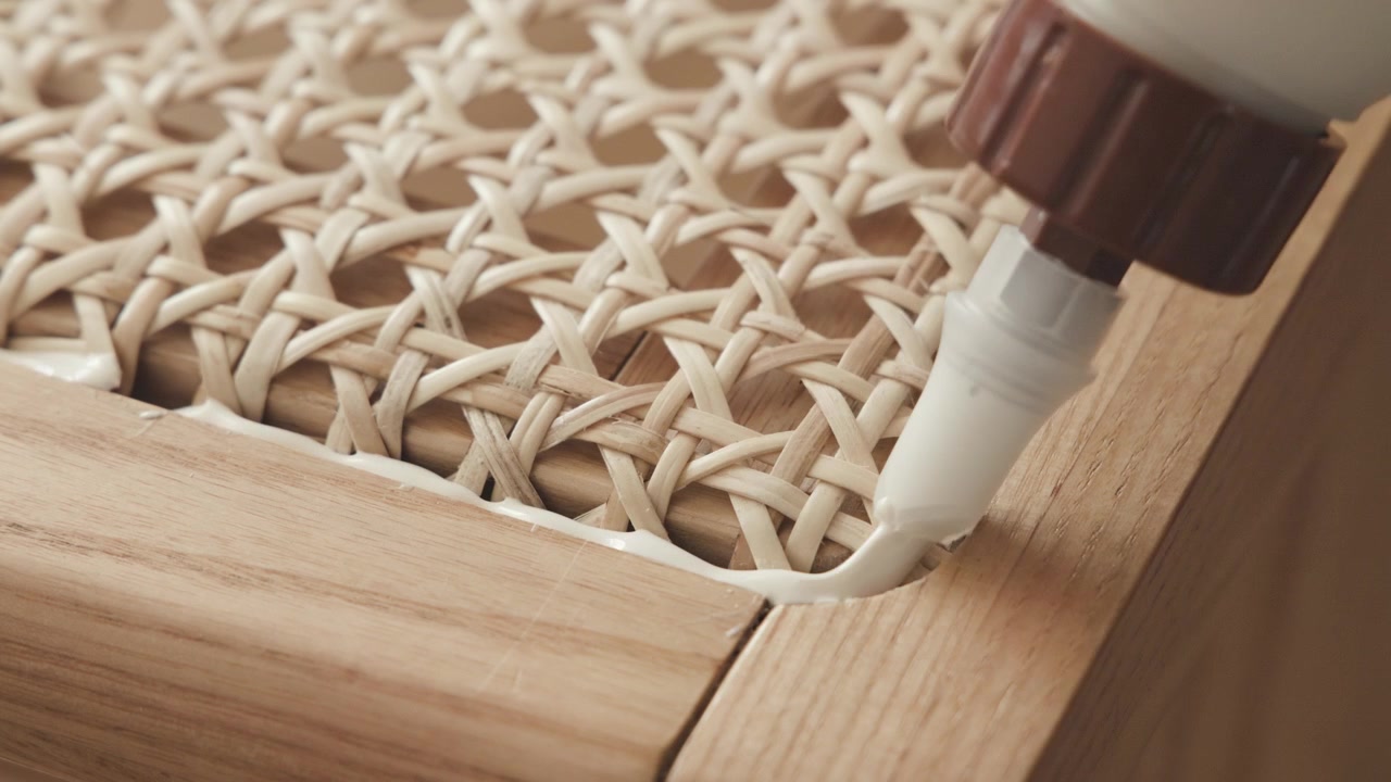 Restauración de silla de ratán, artesano pegando el armazón de la silla