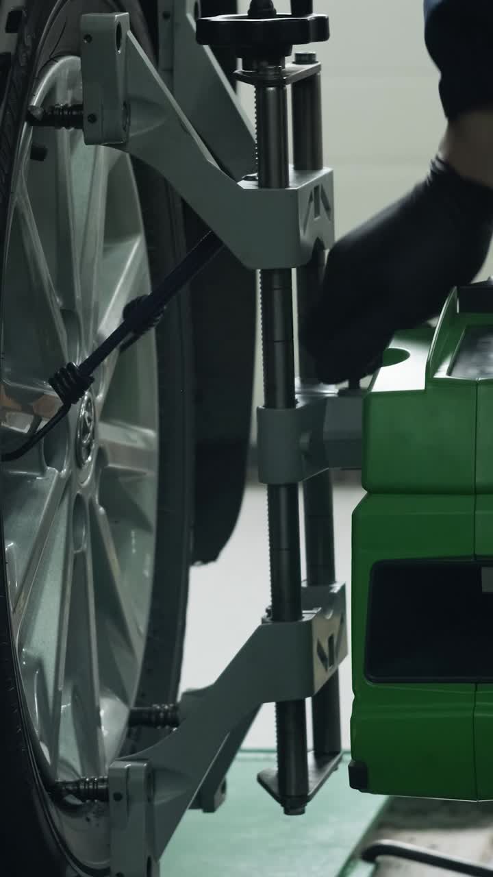 Mechanic Adjusting Wheel Alignment Machine on Car in Auto Service