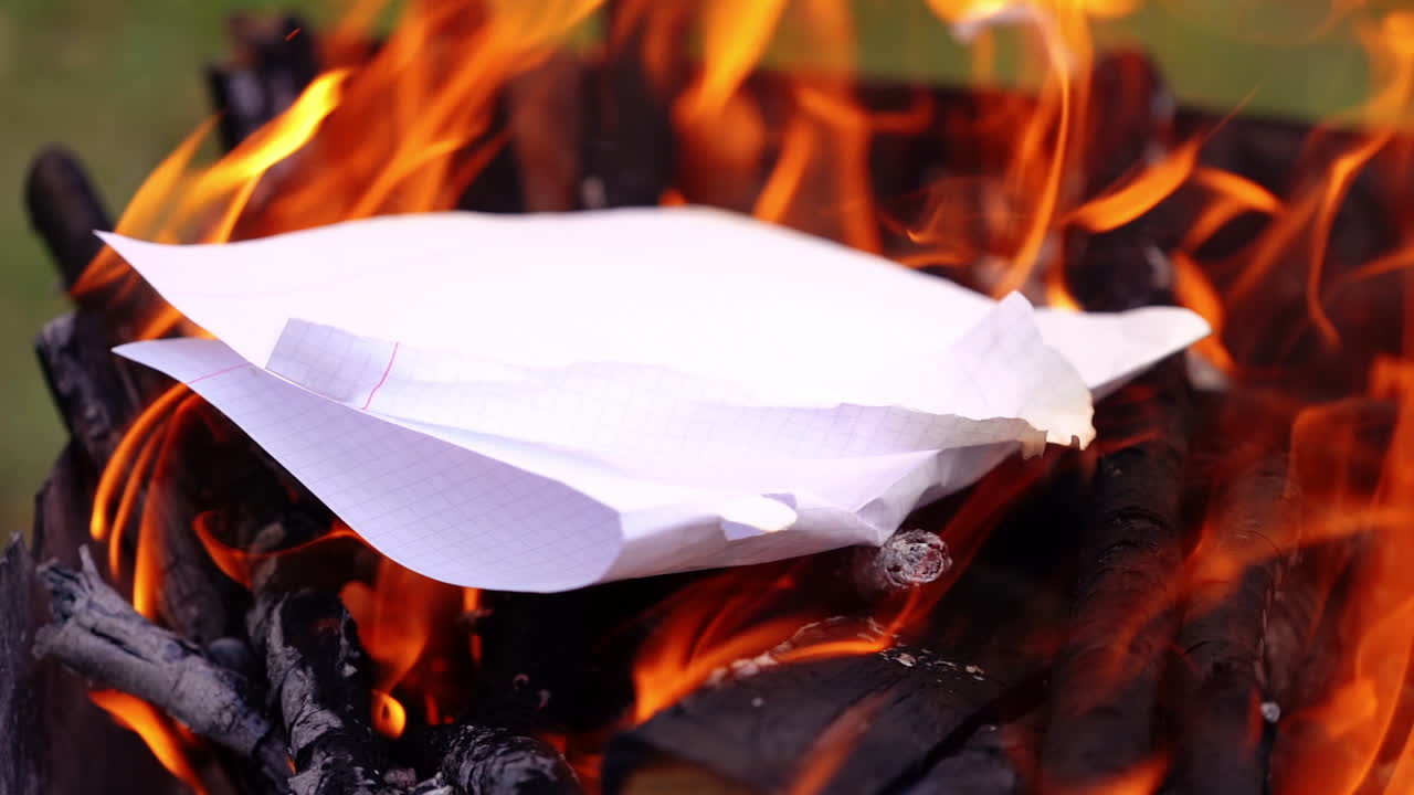 Bright flame over charcoals. White paper falling into the fire and burning out. Wooden logs burning for barbecue. Slow motion.