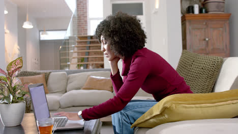 happy biracial woman using laptop at home, slow motion