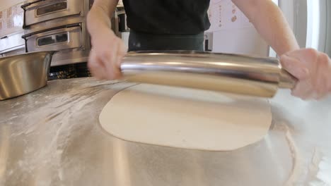 italian pizza chef forming the dough on a floured surface and rolling out a dough