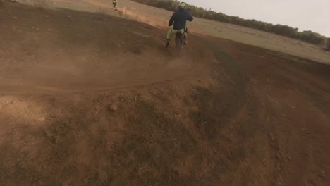 dron dinámico fpv sigue a un motociclista todoterreno en una pista de arena profunda