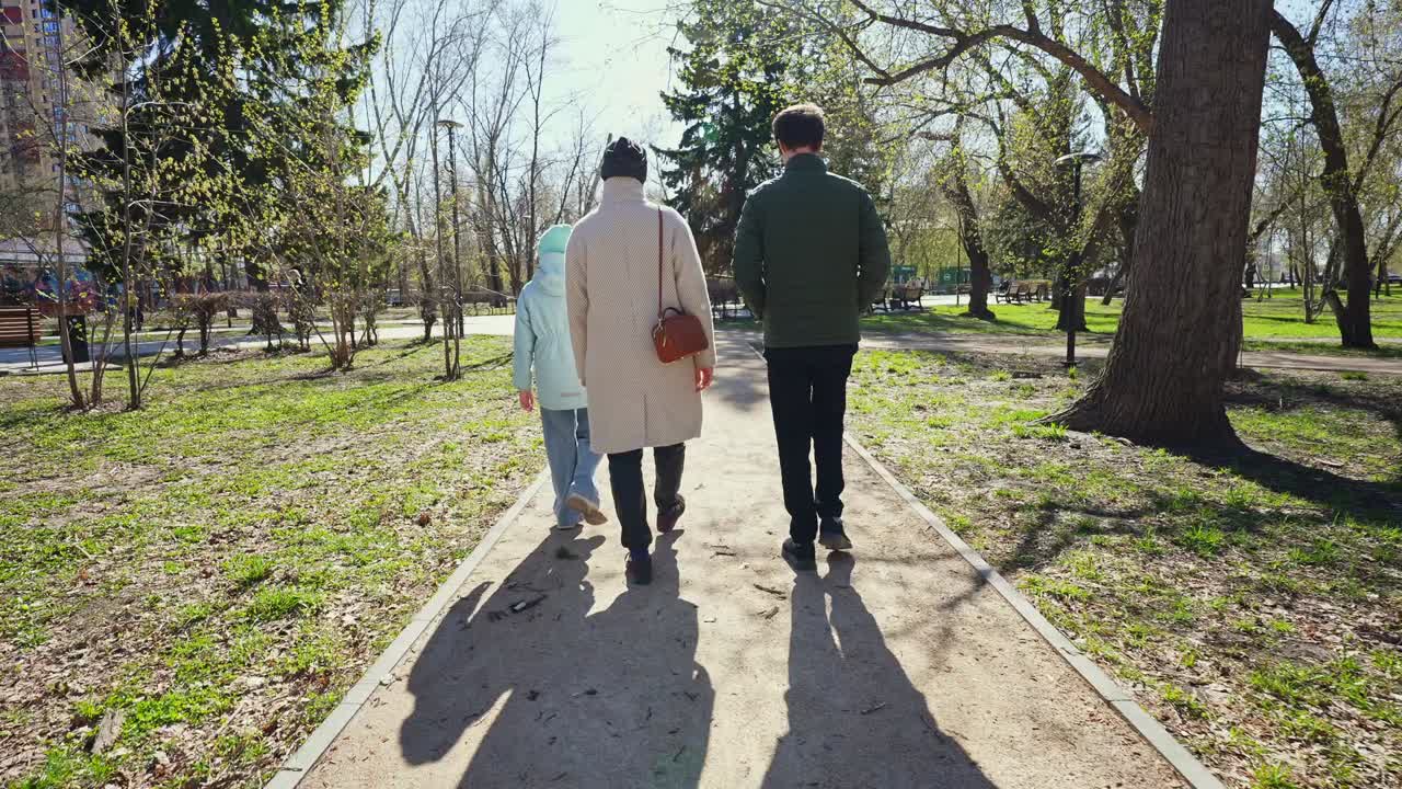 Famiglia che si allontana su un sentiero di un parco soleggiato