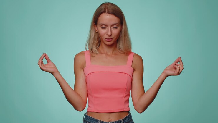 Donna respira profondamente con un gesto mudra, occhi chiusi, meditando con pensieri concentrati e pacifici.