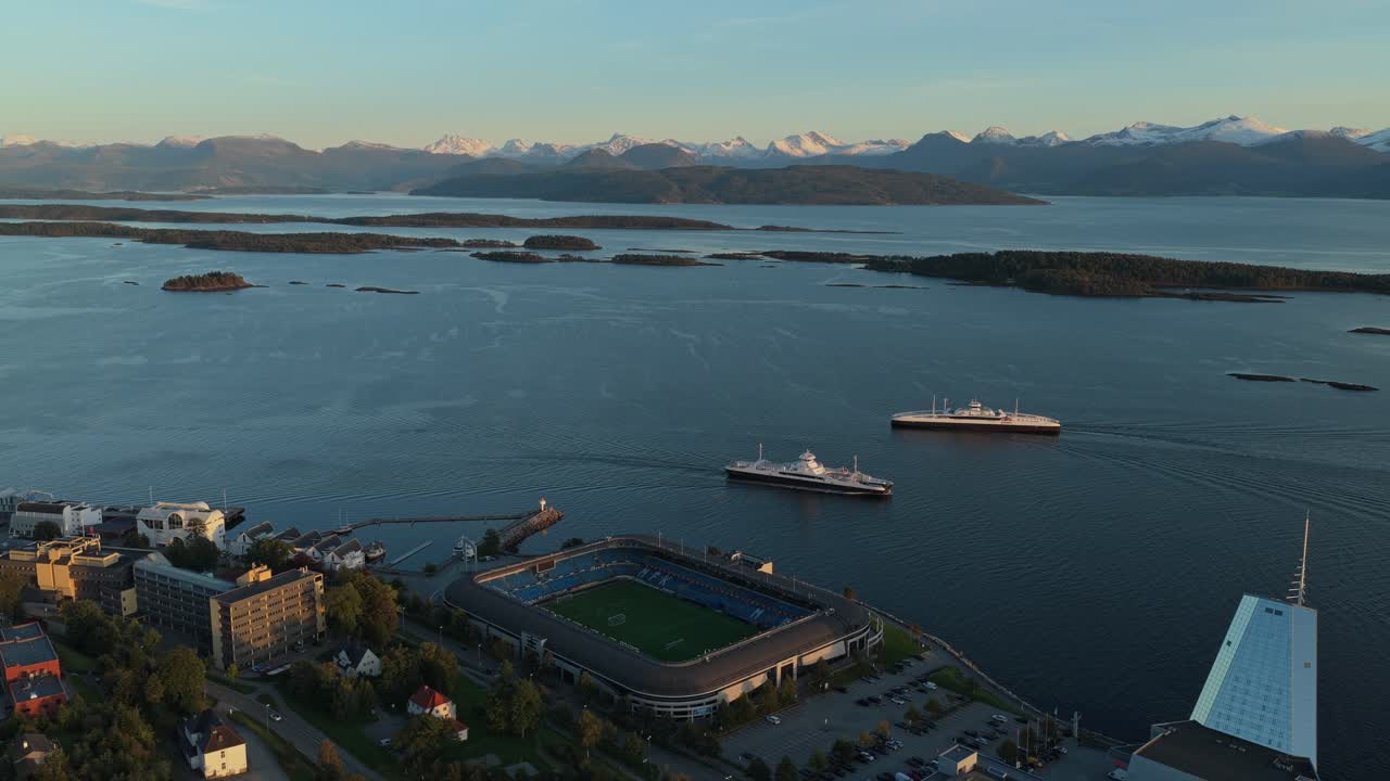 Estádio Molde FK ao pôr do sol com ferries a passar, visto de cima, Noruega