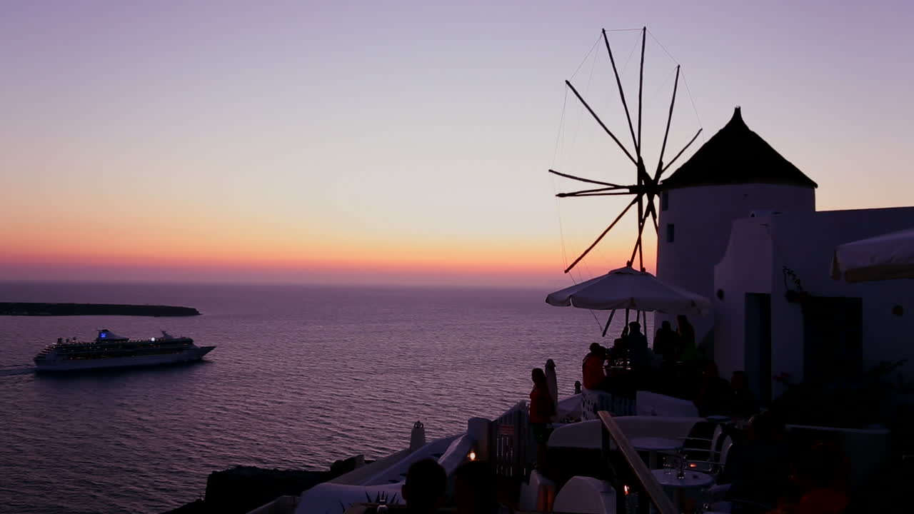 유람선은 황혼에 낭만적인 그리스 산토리니 섬에서 황혼이나 일몰에 풍차를 통과합니다.